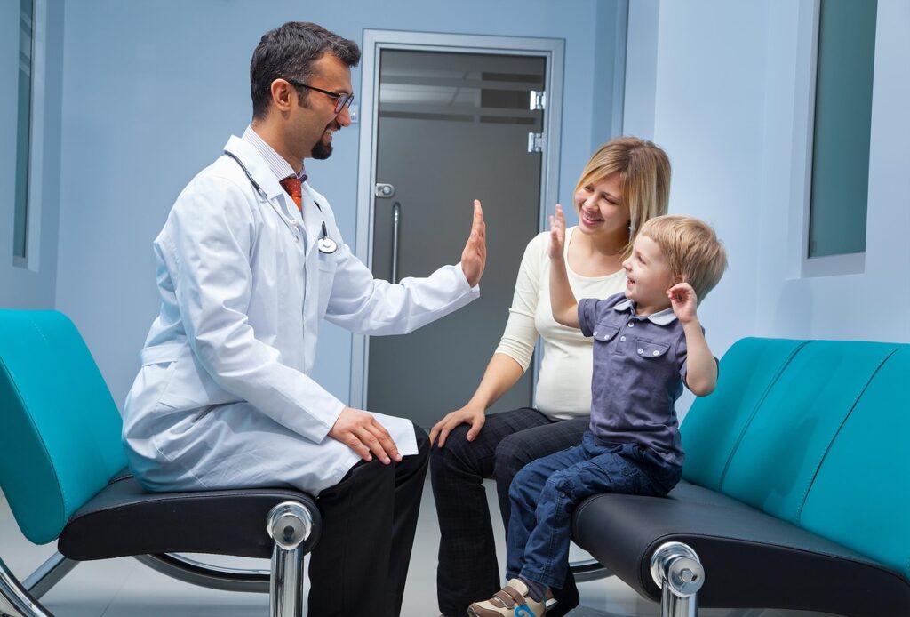 Pediatrician conducting a gentle well-child exam for a smiling toddler.
